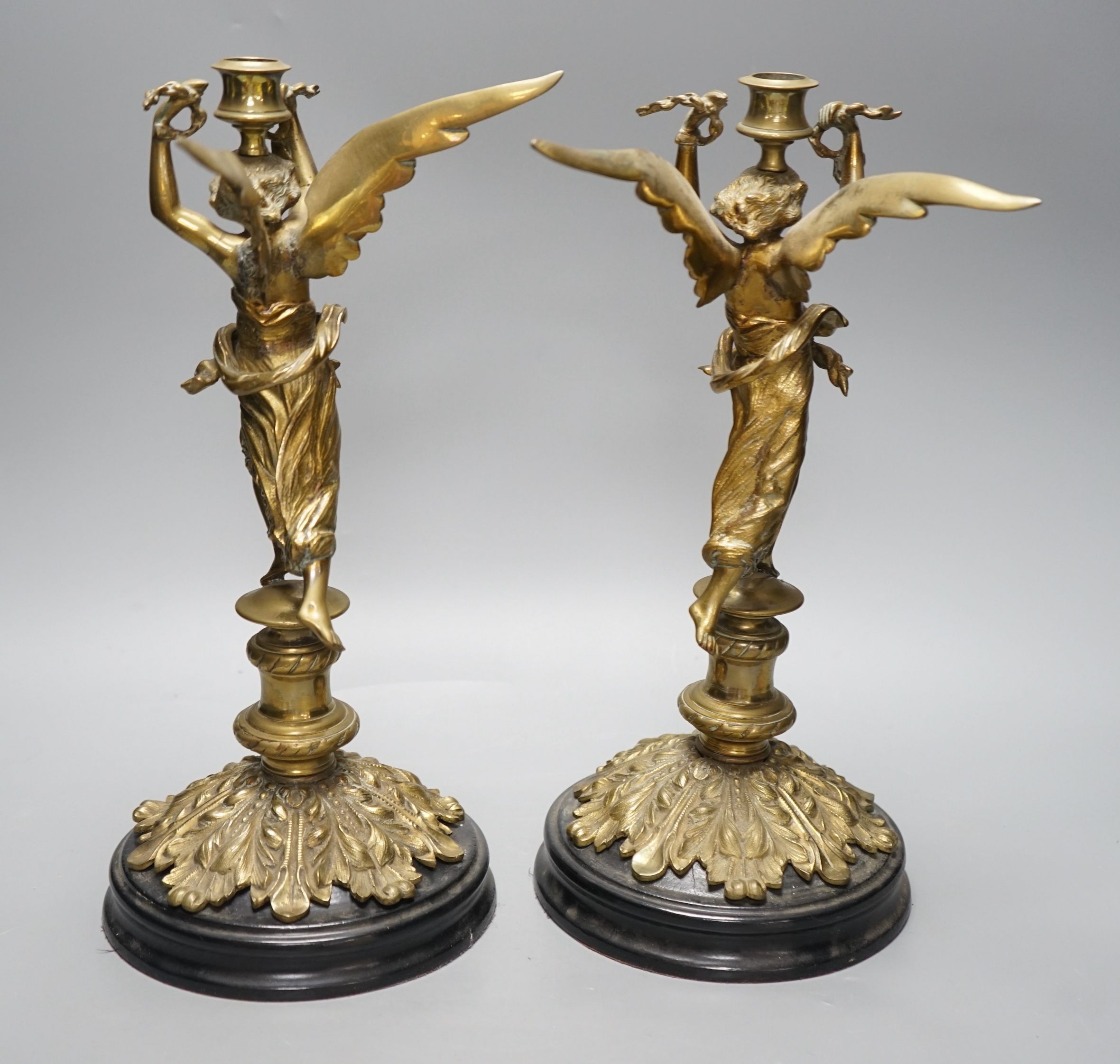 A pair of early 20th century cast brass ‘angel’ candlesticks, 36cms high